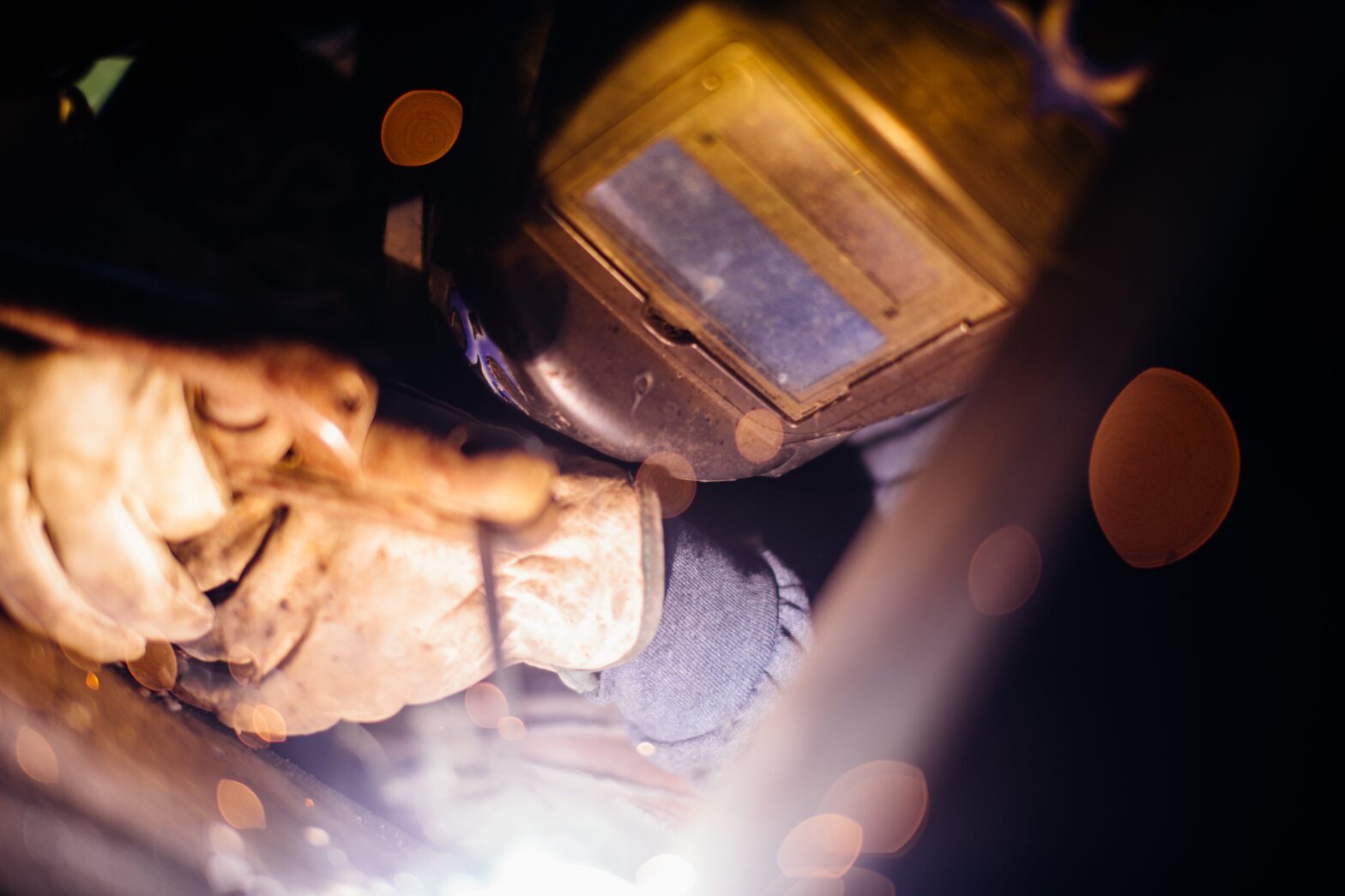 An image of a person wearing a welding helmet and gloves welding