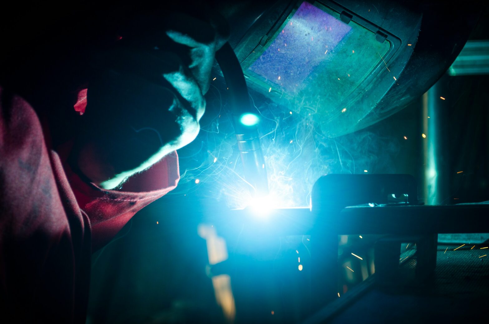 An image of a person using welding equipment and wearing welding helmet